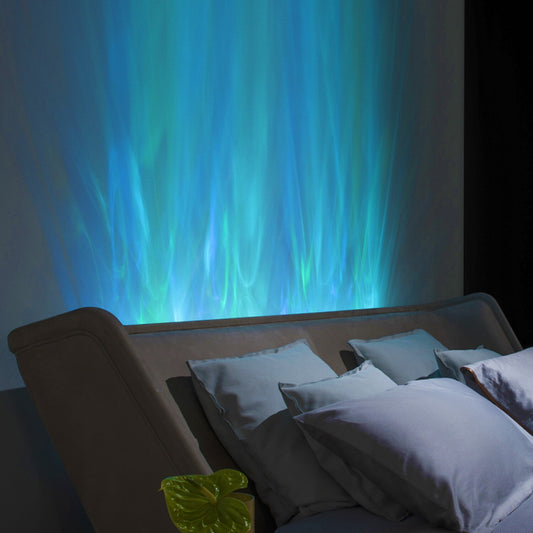 Colorful blue and green wall projector light behind a beige couch with blue and grey pillows.