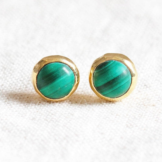 Green malachite and gold stud earrings displayed on a light fabric background.